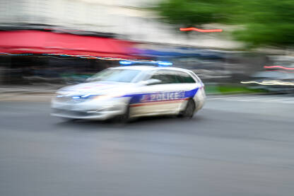 Zamagljena policijska patrola se brzo kreće ulicom. Pogled sa strane na policijski automobil u Francuskoj. Policijsko patrolno vozilo.