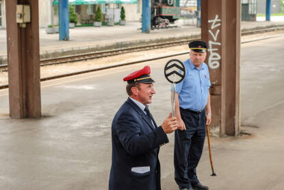 Otpravnik vozova sa palicom na željezničkoj stanici. Radnici na željezničkoj stanici.