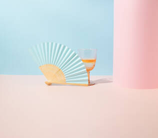 Papirnata lepeza i čaša za piće na geometrijskoj plavoj i ružičastoj pozadini. Minimalni koncept.