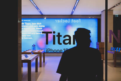 Izlog Apple shopa u gradu noću. Nedavno objavljen iPhone 15. Titanium. Prodavnica pametnih telefona reklamira novi model telefona.