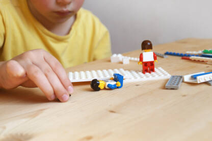 Dječak koji se na stol igra sa lego kockicama.