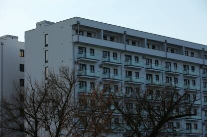 Veliki beli hotel sa balkonima, drvece ispred hotela
