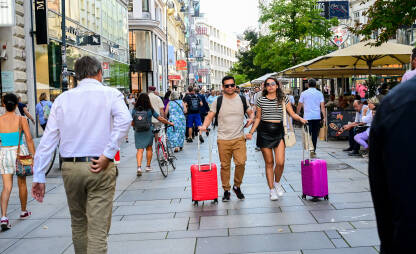 Turisti šetaju gradom s prtljagom. Putnici nose kofere i ruksake. Putnici hodaju s prtljagom prema stanici. Par putuje s koferima.