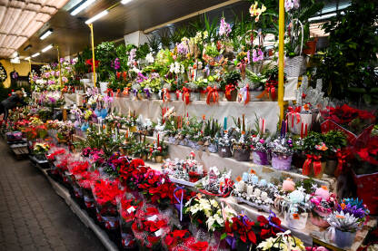 Cvijeće na prodaju na lokalnoj pijaci. Cvjećara s buketima, cvijećem i svijećama. Štand na pijaci koji prodaje cvijeće i ukrase.