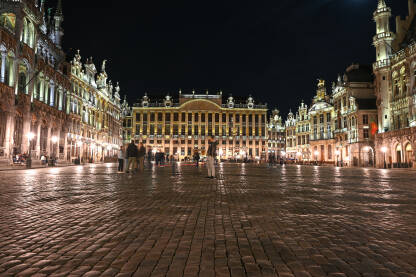 Brisel, Belgija: Ljudi na glavnom trgu u centru grada noću. Brussels - Grand Place je centralni trg. Osvijetljene historijske zgrade.
