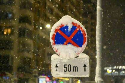 Znak zabrane stajanja ili parkiranja prekriven snijegom. Saobraćajni znak prekriven snijegom zimi.