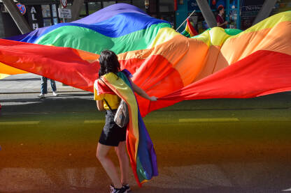 Djevojka drži ogromnu LGBT, duginu zastavu na Povorci ponosa 2022.