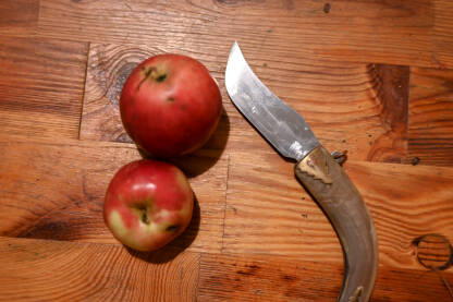 Stari nož i dvije jabuke na stolu.
