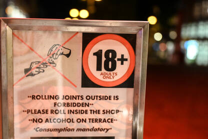 Znak: "18+ samo za odrasle. Motanje džointa je dozvoljeno samo unutar objekta". Znak na ulazu u coffee shop gdje je legalizirana upotreba marihuane u Amsterdamu, Holandija.
