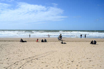Ljudi se zabavljaju na plaži. Obala Sjevernog mora u Hagu. Turisti na pješčanoj plaži.