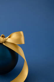 Plava božićna, novogodišnja ukrasna kuglica sa žutom mašnom.