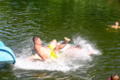 Ljudi se zabavljaju na vodenom toboganu. Turisti se kupaju u rijeci. Zabava na vodi.