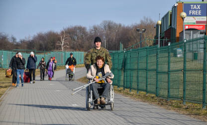 Policajac pomaže ženi u invalidskim kolicima da pređe iz Ukrajine u Poljsku. Prelaz Medyka na granici Ukrajina-Poljska.