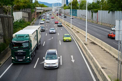 Automobili i kamioni se kreću autoputem u Austriji. Vozila u pokretu. Vožnja automobilom na autoputu. Kretanje automobila, autobusa i kamiona po autoputu. Prijevoz. Transport. Cestovni saobraćaj