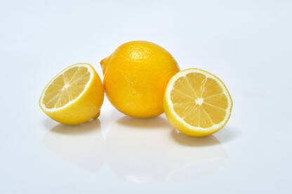 Limun i narezane kriške limuna na bijeloj pozadini
