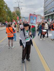 Penzioner sa transparentom u ruci i obilježjima na protestima u Sarajevu zbog genocida u Palestini.