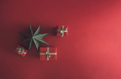 Crvene kutijice i papirna zelena jelka na crvenoj podlozi sa praznim prostorom, Božić, praznik, koncept