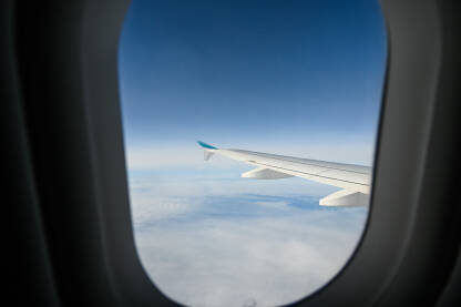 Krilo aviona, pogled kroz prozor. Let mlaznim avionom iznad bijelih oblaka.