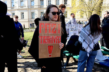 Žena sa natpisom "Pazi tramvaj" drži transparent upozorenja