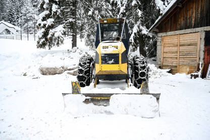 Čišćenje snijega. Traktor s ralicom za snijeg. Čišćenje cesta tijekom zime. Ralica.