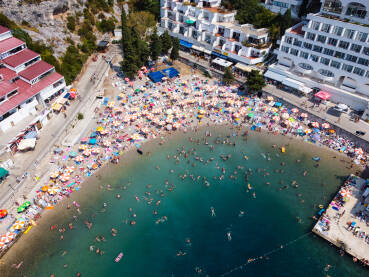 Veliki broj turista na plažu i u moru na vrhuncu turističke sezone. Gomila ljudi koji se kupa u moru tokom ljeta. Ljudi u kupaćim kostimima na obali. Neum, Bosna i Hercegovina, snimak dronom.