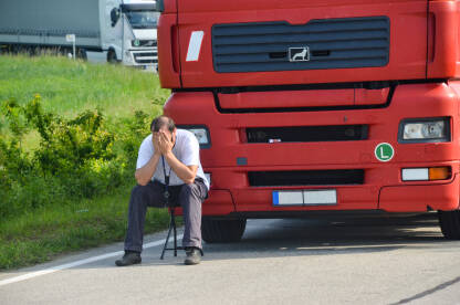 Očajni vozač ispred svog kamiona. Tužan i nervozan čovjek drži glavu rukama. Protest vozača kamiona. Zabrinuti radnik. Kolona kamiona u saobraćajnoj gužvi na granici.