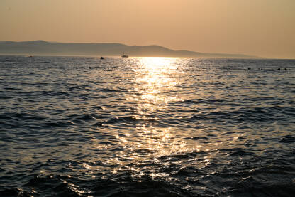Zalazak sunca na moru. Brodice na vodi. Valovi na moru u predvečerje.