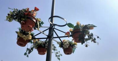 Saksije sa vještačkim cvijećem.Plastično cvijeće u saksijama, okačeno na banderu. Saksije sa umjetnim cvijećem na metalnom stubu.