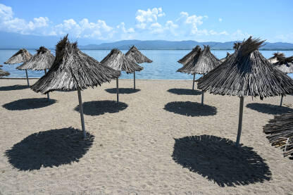 Suncobrani na plaži. Dojransko jezero, Sjeverna Makedonija. Pješčana plaža pored jezera.