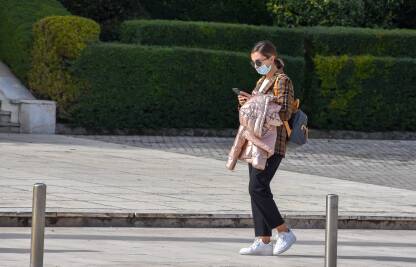 Žena hoda ulicom sa maskom na licu zbog prevencije širenja virusa korona.