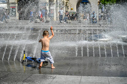 Dječak se osvježava na fontani. Mladić se osvježava pod vodom tokom vrelog ljetnog dana. Toplotni talas u gradu. Dječak poprskan vodom.