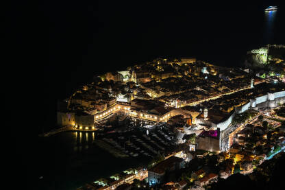 Dubrovnik noću, panorama. Stare gradske zidine i kule u Dubrovniku, Hrvatska. Panoramski pogled na historijski grad na jadranskoj obali. UNESCO-va svjetska baština. Popularna turistička destinacija.