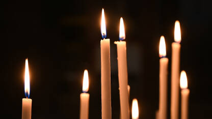 Zapaljene svijeće u katedrali. Upaljene svijeće u katoličkoj crkvi s crnom pozadinom.