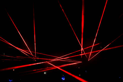 Laserska svjetla na koncertu. Crvena laserska svjetla na bini noću. Apstraktna pozadina. Laserski snop.