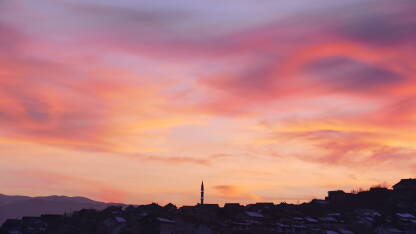 Zalazak sunca iznad Sarajeva. Veličanstvene boje na nebu iznad grada, sa minaretom u pozadini.