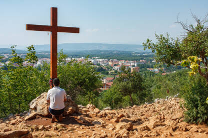 Hodočasnik se moli ispred krsta na Križnom putu u Međugorju.