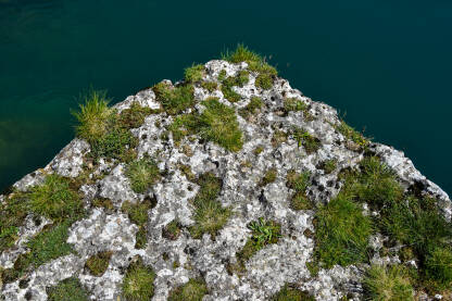 Stijena iznad modro-zelene rijeke. Kamen pun mahovine iznad vode.