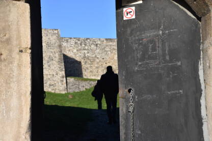 Ulaz u tvrđavu sa znakom zabranjivanja nošenja oružja sa siluetom muškarca i žene u pozadini.