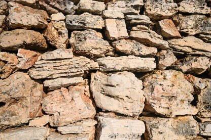 Suhi kameni zid, izbliza. Kameni zid u blizini kuće u prirodi. Tradicionalni suhozid u polju na zalasku sunca. Srednjovjekovni kameni zid.