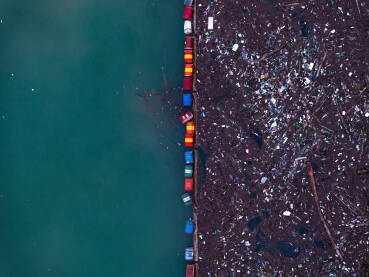 Razni oblici komunalnog otpada nagomilani u rijeci Drini, vidljivi na površini i uz obalu.