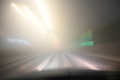 Zamućena fotografija vožnje automobilom po maglovitom vremenu. Jako zagađenje zraka. Teški uslovi za vožnju noću. Pogled na cestu kroz vjetrobransko staklo automobila. Magla.
