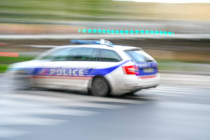 Zamućena policijsko patrolno vozilo se brzo kreće ulicom u Parizu, Francuska. Bočni pogled na policijski automobil s natpisom "Police".