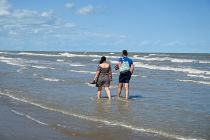 Par hoda po pješčanoj plaži i vodi.