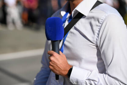 Novinar drži mikrofon dok izvještava uživo. Novinar drži mikrofon dok izvještava uživo. TV reporter.