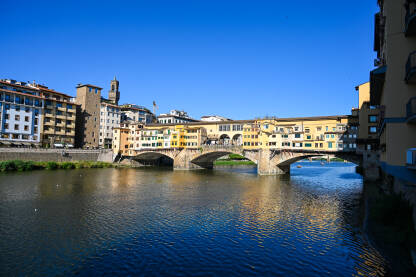 Firenze, Italija: most Vecchio preko rijeke Arno. Historijske građevine uz rijeku. Popularno turističko odredište.