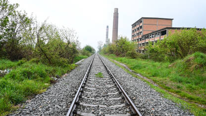 Željezničke šine pored napuštenog industrijskog kompleksa. Željeznička pruga u blizini stare fabrike.