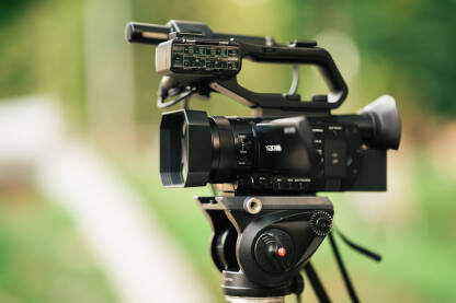 Krupni plan profesionalne video kamere sa zelenkastom zamagljenom pozadinom.
Snimanje događaja na terenu video kamerom.