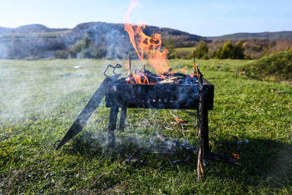 Otvorena vatra na roštilju. Opasnost od požara. Vatra gori u roštilju u prirodi.