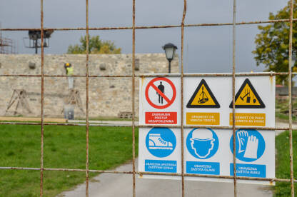 Znakovi sigurnosti i upozorenja na gradilištu. Simboli na žičanoj ogradi u blizini zgrade u izgradnji.
