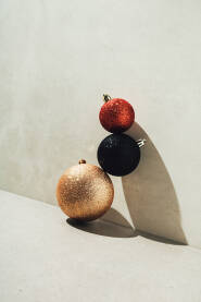 Tri božićne / novogodišnje kuglice naslagane uz betonski zid.
